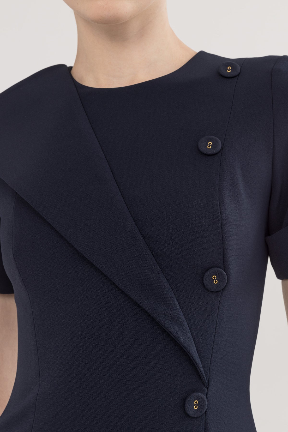 Close-up of navy midi dress with refined neckline, button detail, and sculpted bodice