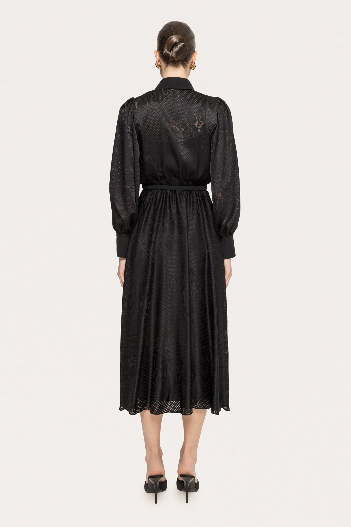 Back view of a black belted midi dress with long sleeves and softly flared silhouette