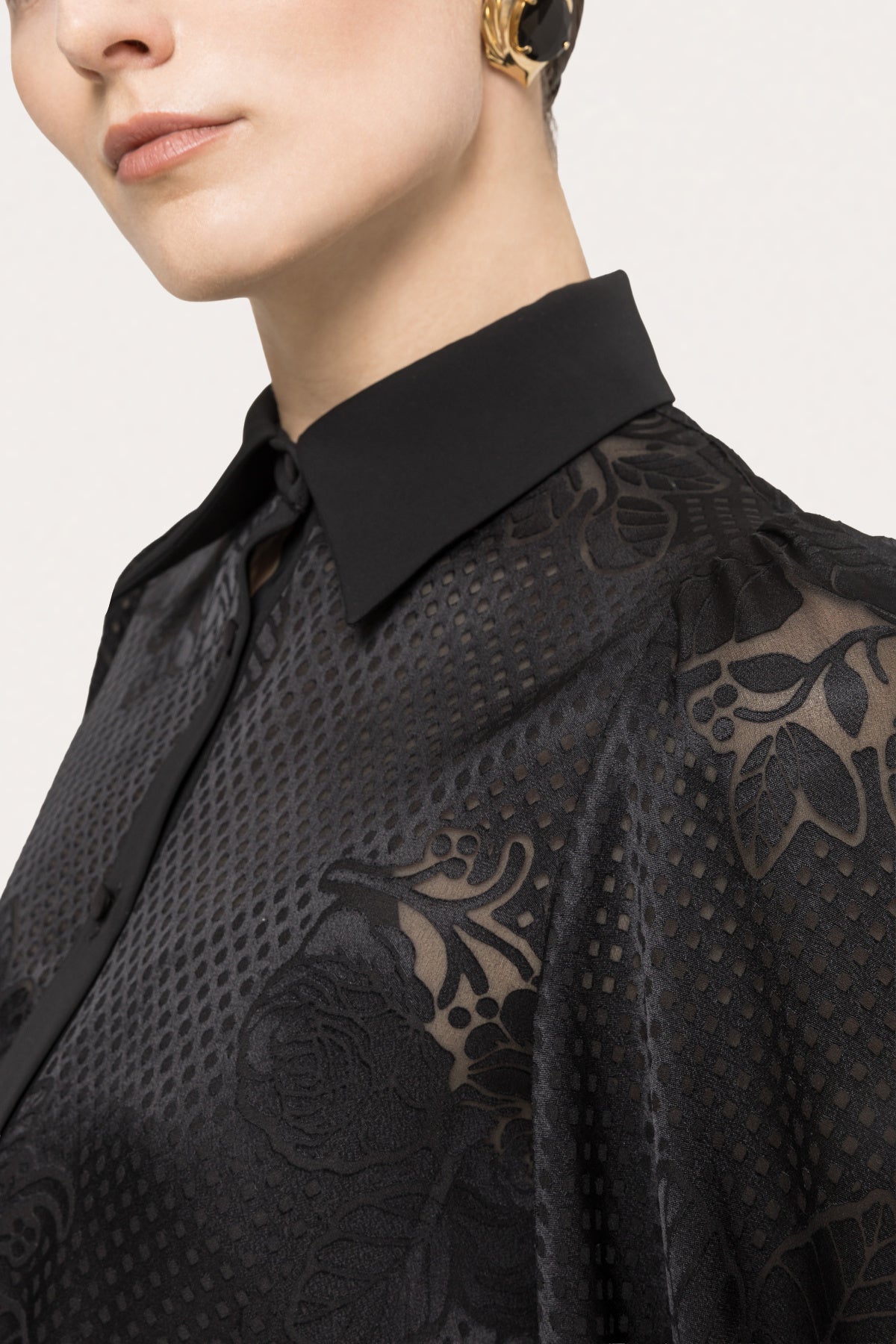 Close-up of the pointed collar and tonal floral textured fabric on a black long sleeve midi dress