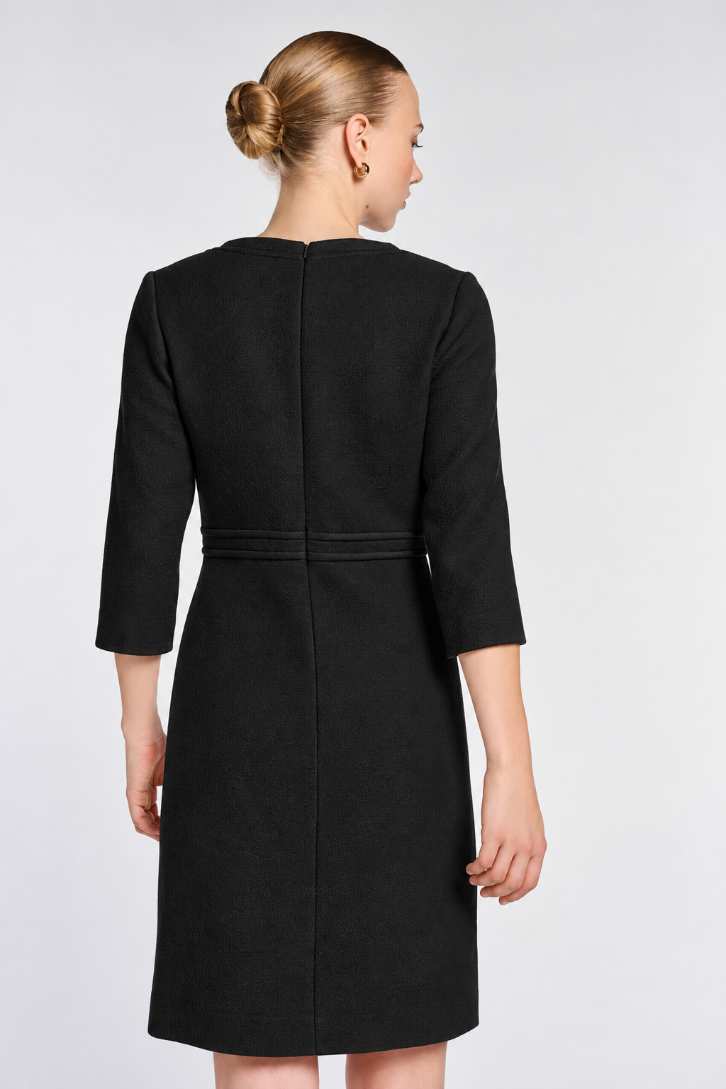 Close-up of the back of the black wool dress showing waist trim and the concealed zipper