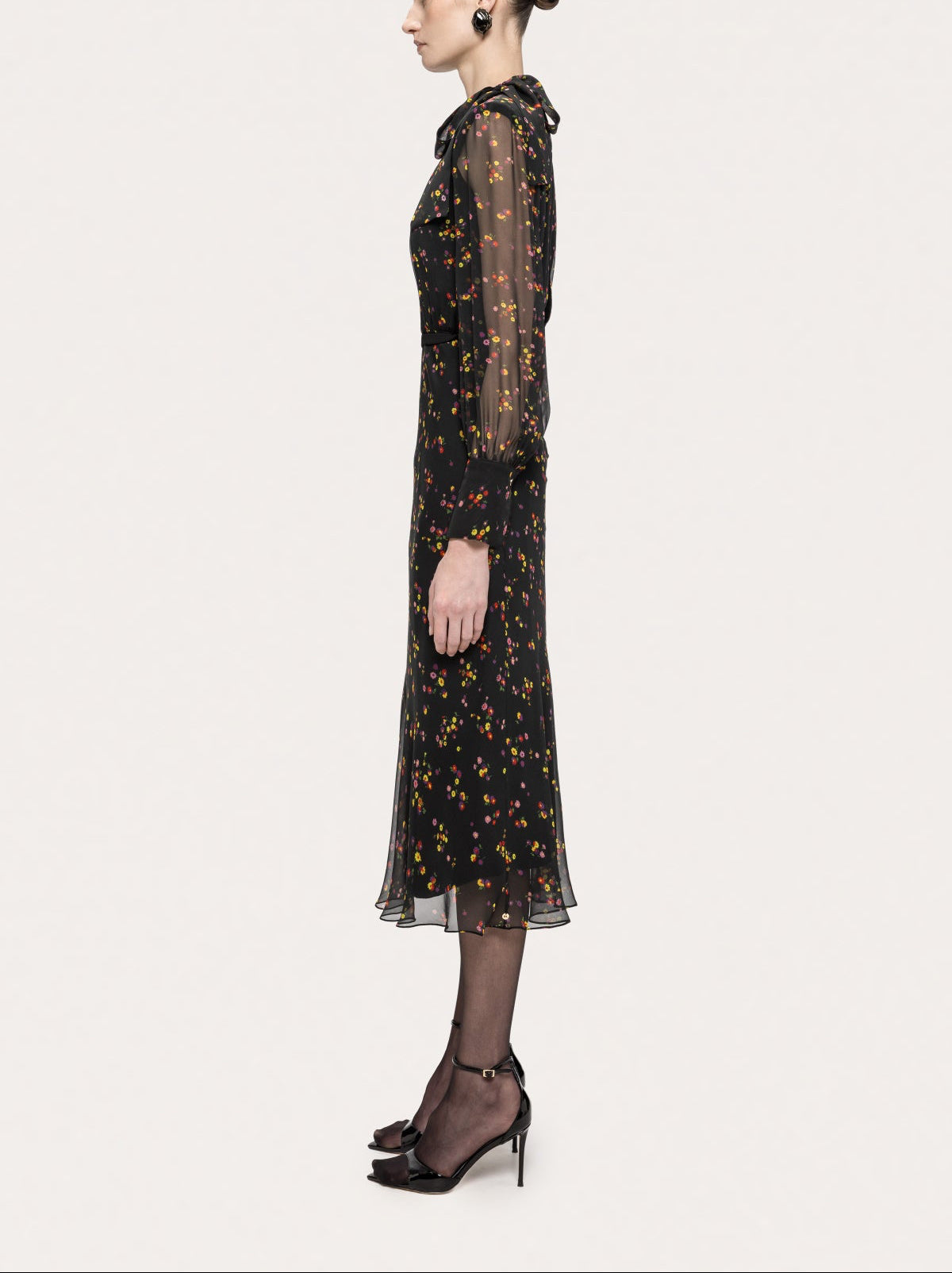 Side view of the NISSA black floral silk midi dress showing the shoulder bow and mid-calf length
