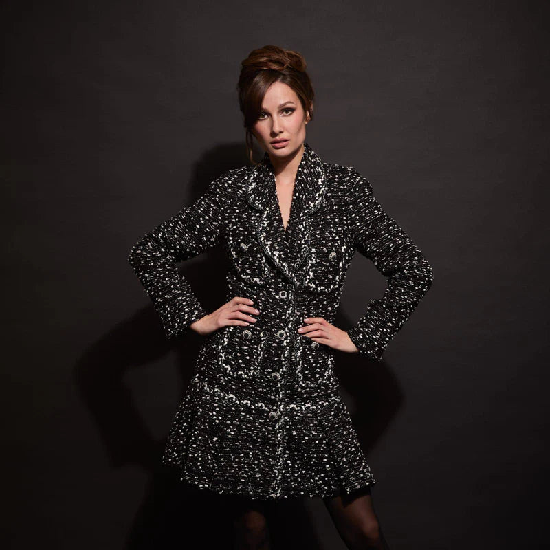 Model wearing black and white tweed coat dress with notched lapel, long sleeves and A‑line flounced hem