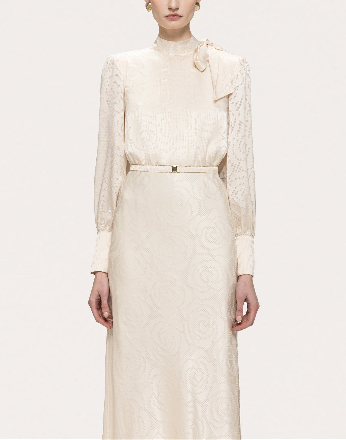 NISSA cream satin bow-neck midi dress showing long sleeves, a softly bloused bodice and a slim waist belt.