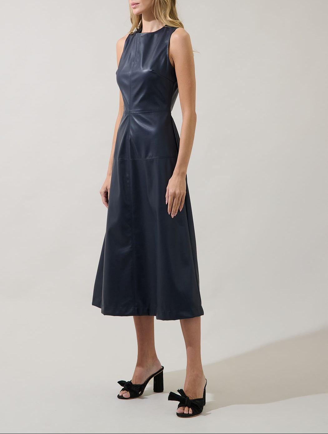 Three-quarter view of the Sugarlips Strella navy faux leather midi dress showing the fitted waist and flared skirt.
