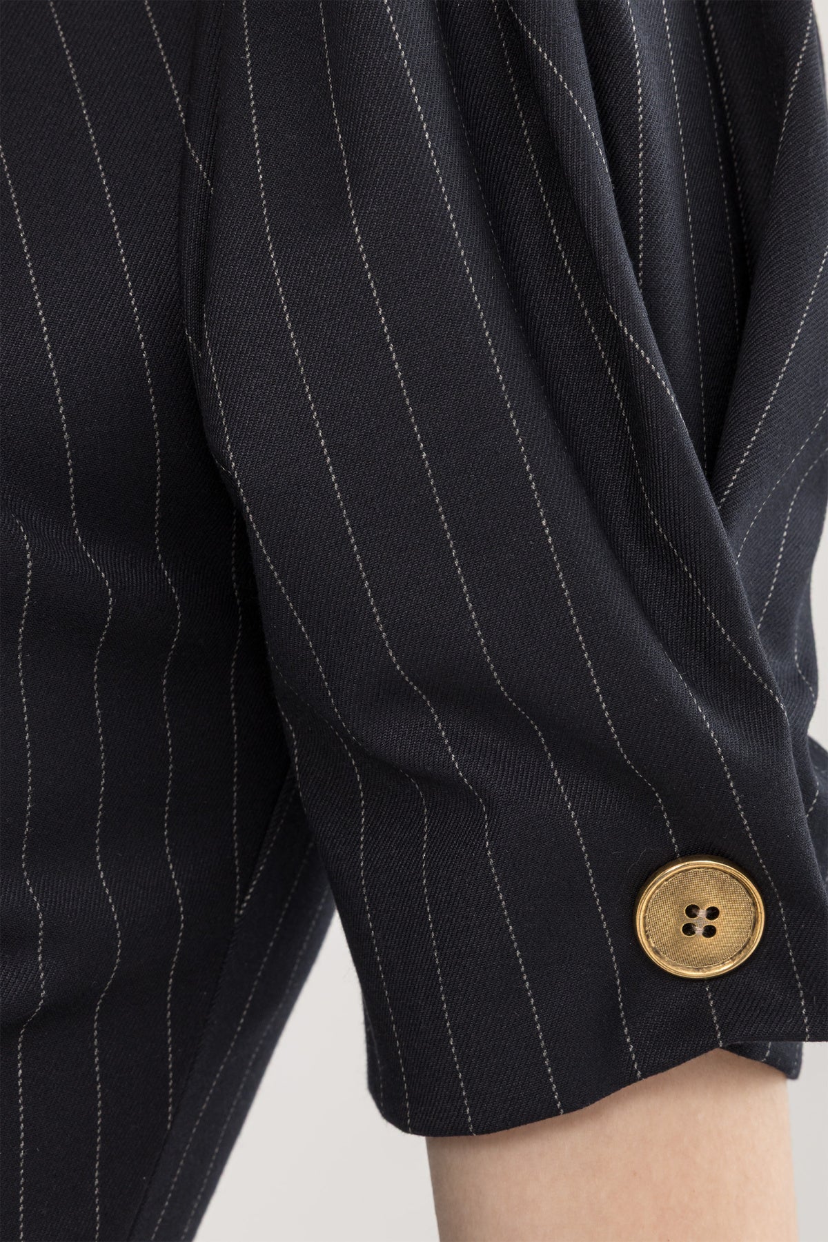 Close-up of black pinstripe puff sleeve with gold-tone button detail