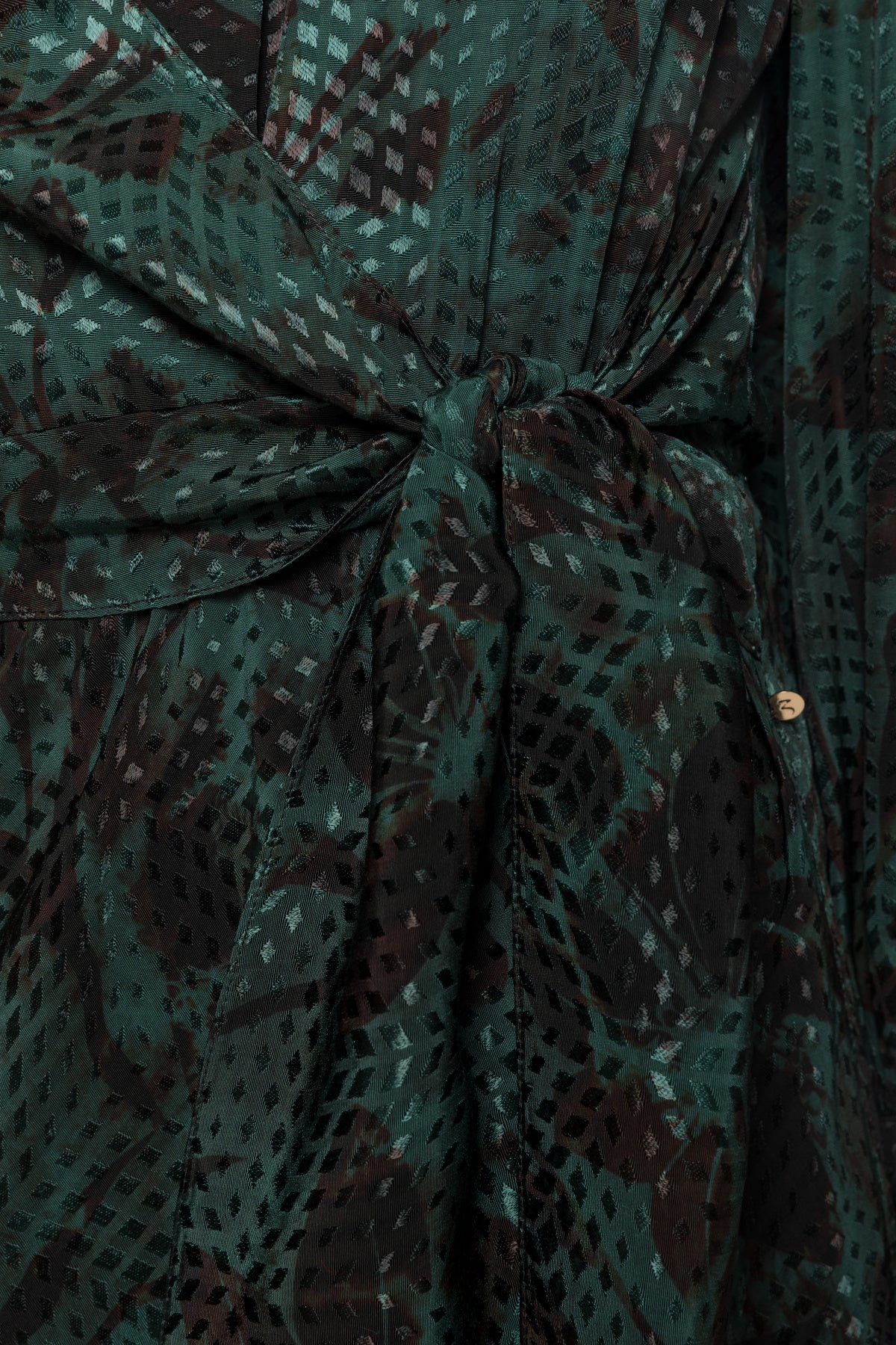 Close-up of the matching tie waist and textured green floral fabric on NISSA dress