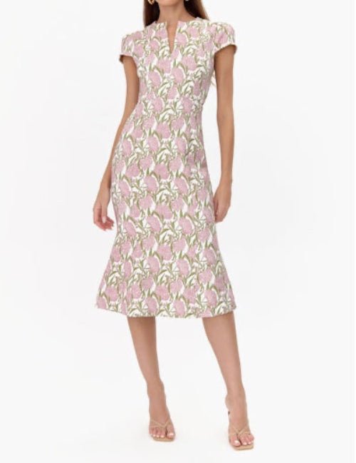 Woman wearing a pink floral jacquard cap sleeve midi dress, ideal for spring weddings and elegant gatherings.