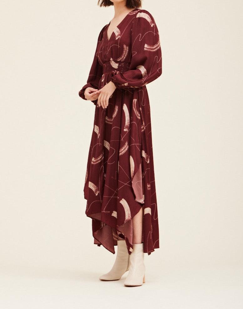 Three-quarter view of the Grade & Gather Vino satin maxi dress with an asymmetrical hem, styled with cream boots.