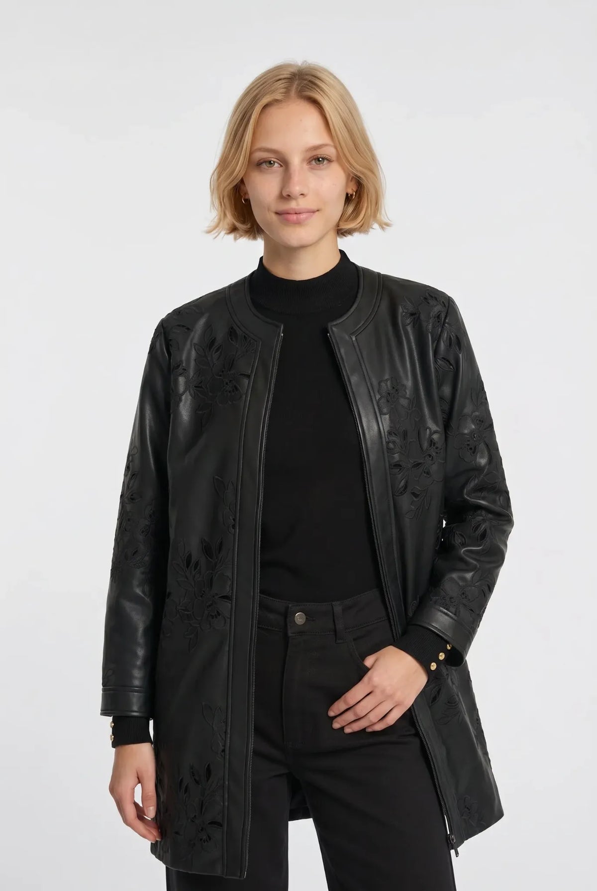 Front detail of a Weill Paris black faux leather coat showing its collarless neckline, floral embroidery and long sleeves.