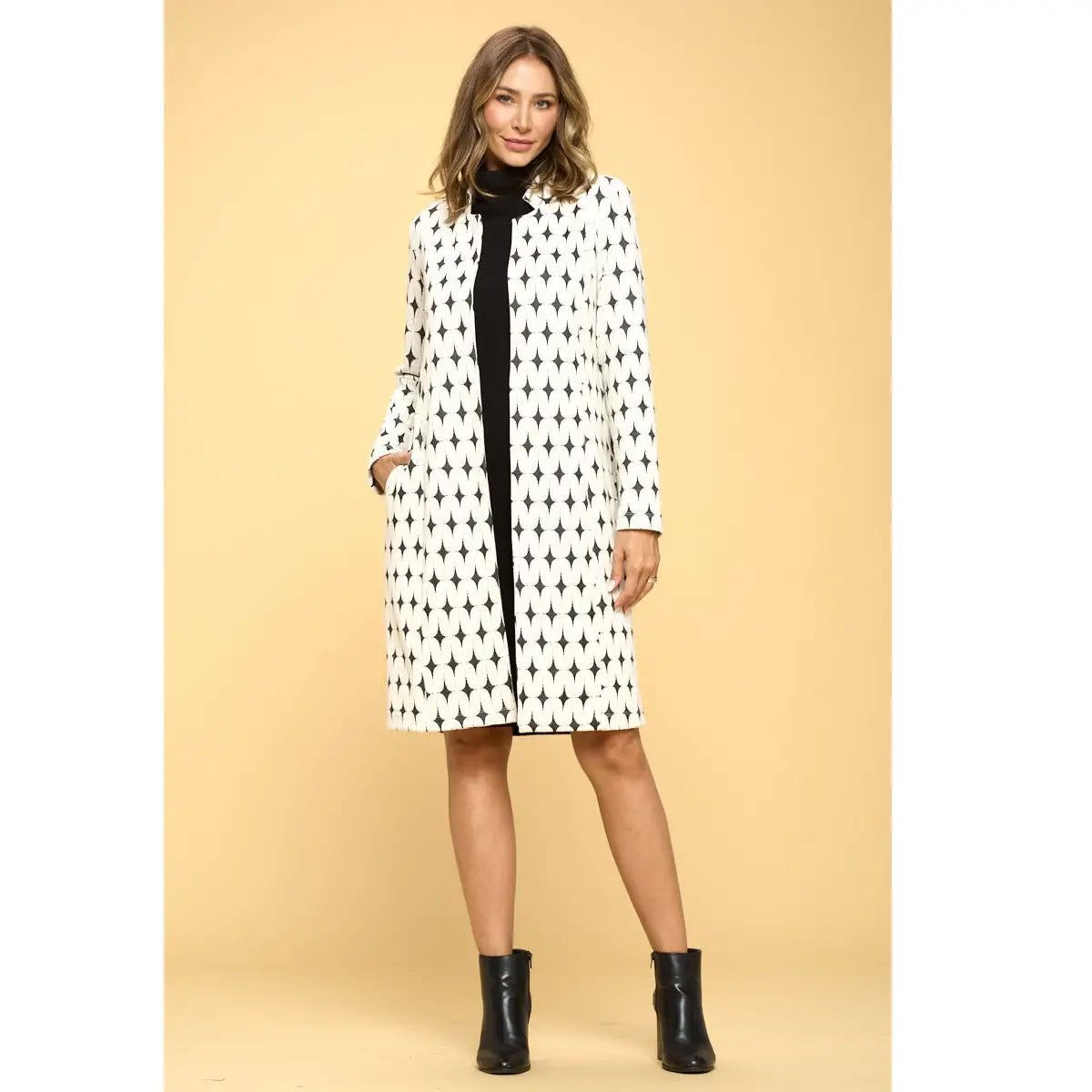 Front view of Renee C ivory and black geometric open-front longline jacket with long sleeves, worn over a black dress.
