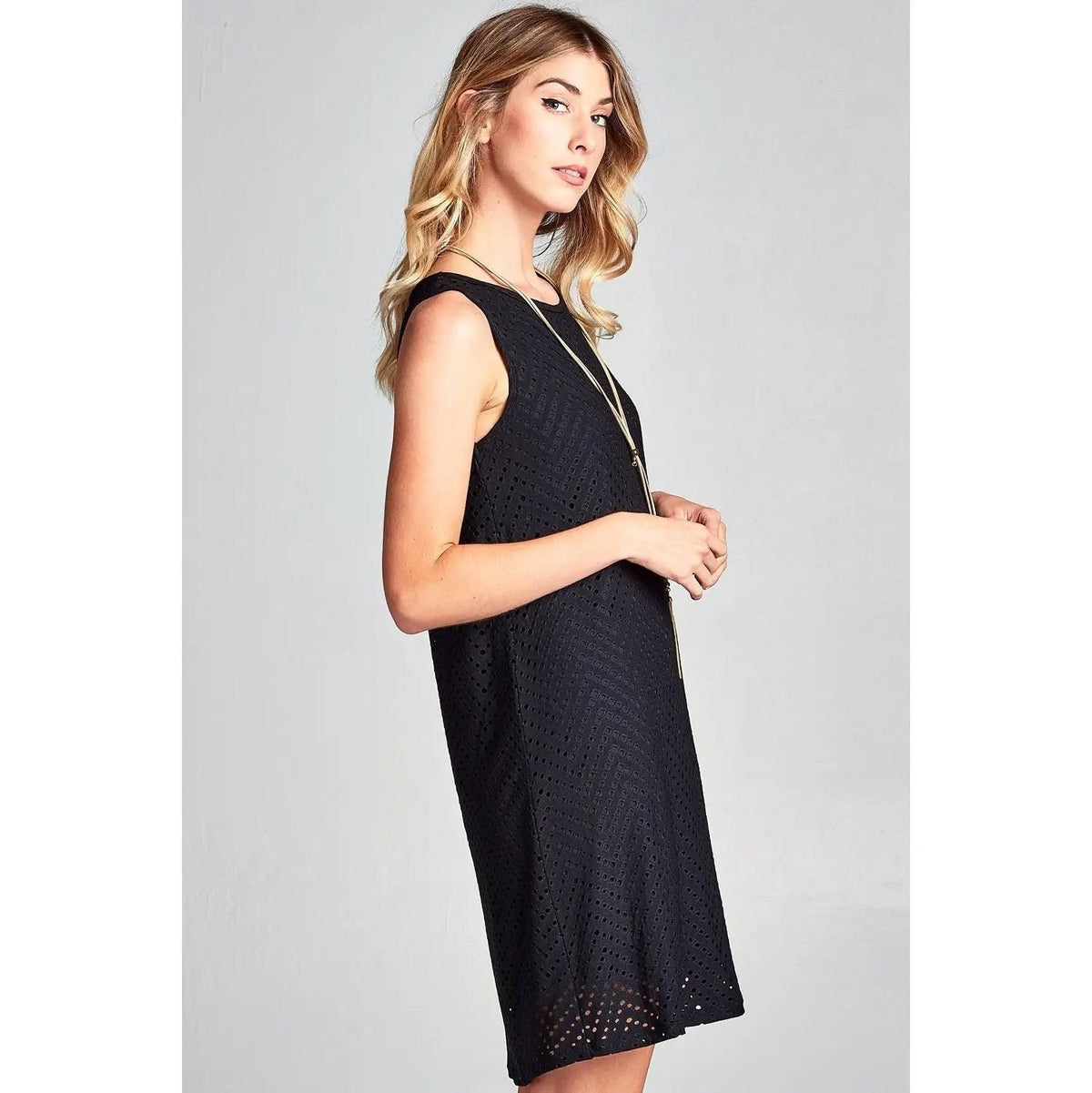 Close side view of Renee C black mini dress showing the eyelet texture and openwork hem.