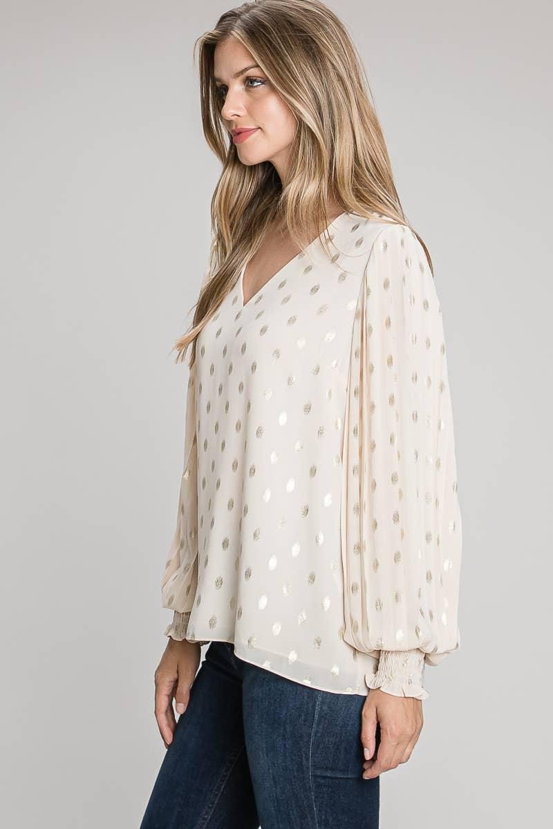 Side view of the champagne blouse showing gold-tone foil dots, pleated sleeve detailing and smocked cuffs with ruffled edges.