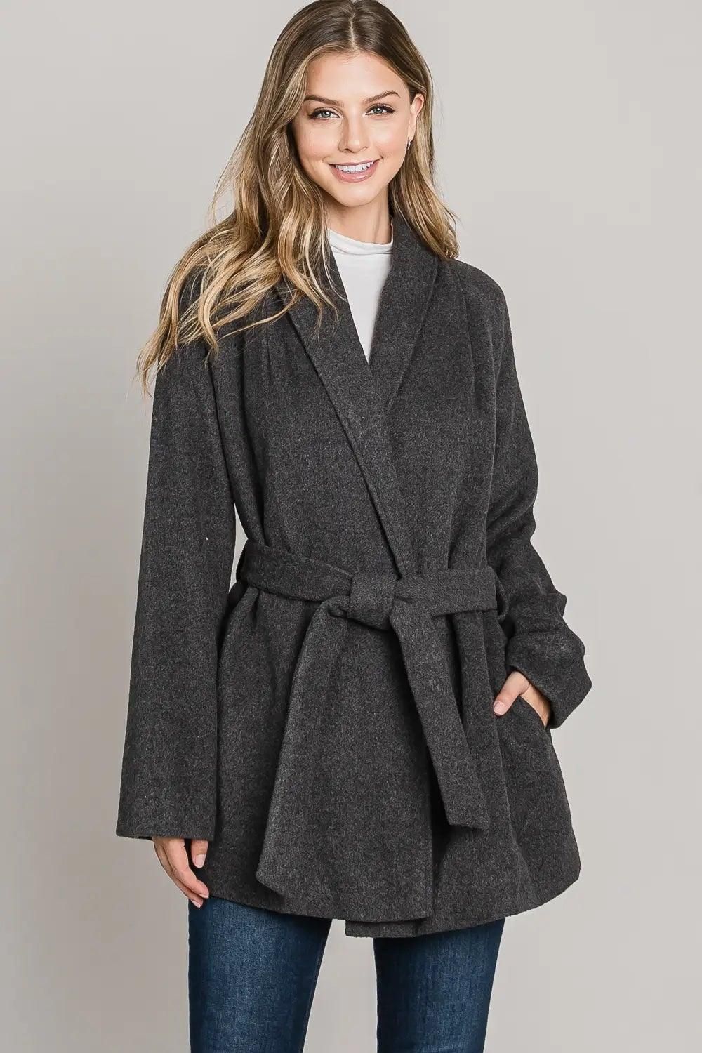 Front view of the Allie Rose charcoal belted wrap jacket with a lapel collar, long sleeves and side pockets.