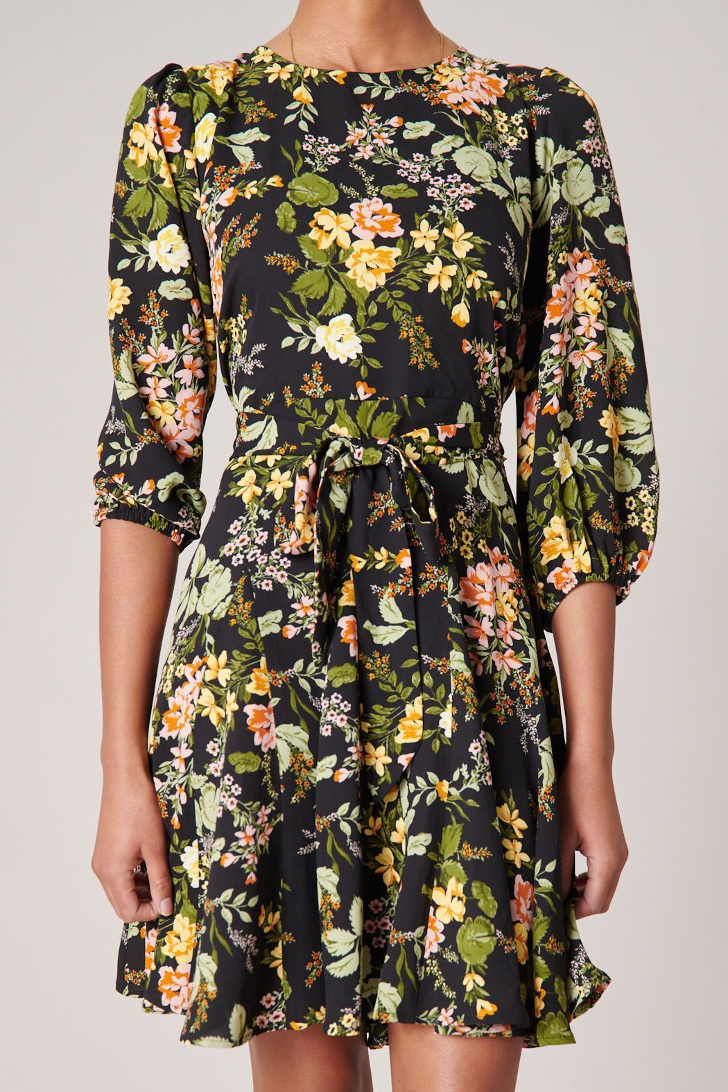 Close-up of black floral print, jewel neckline, and tie waist on mini dress