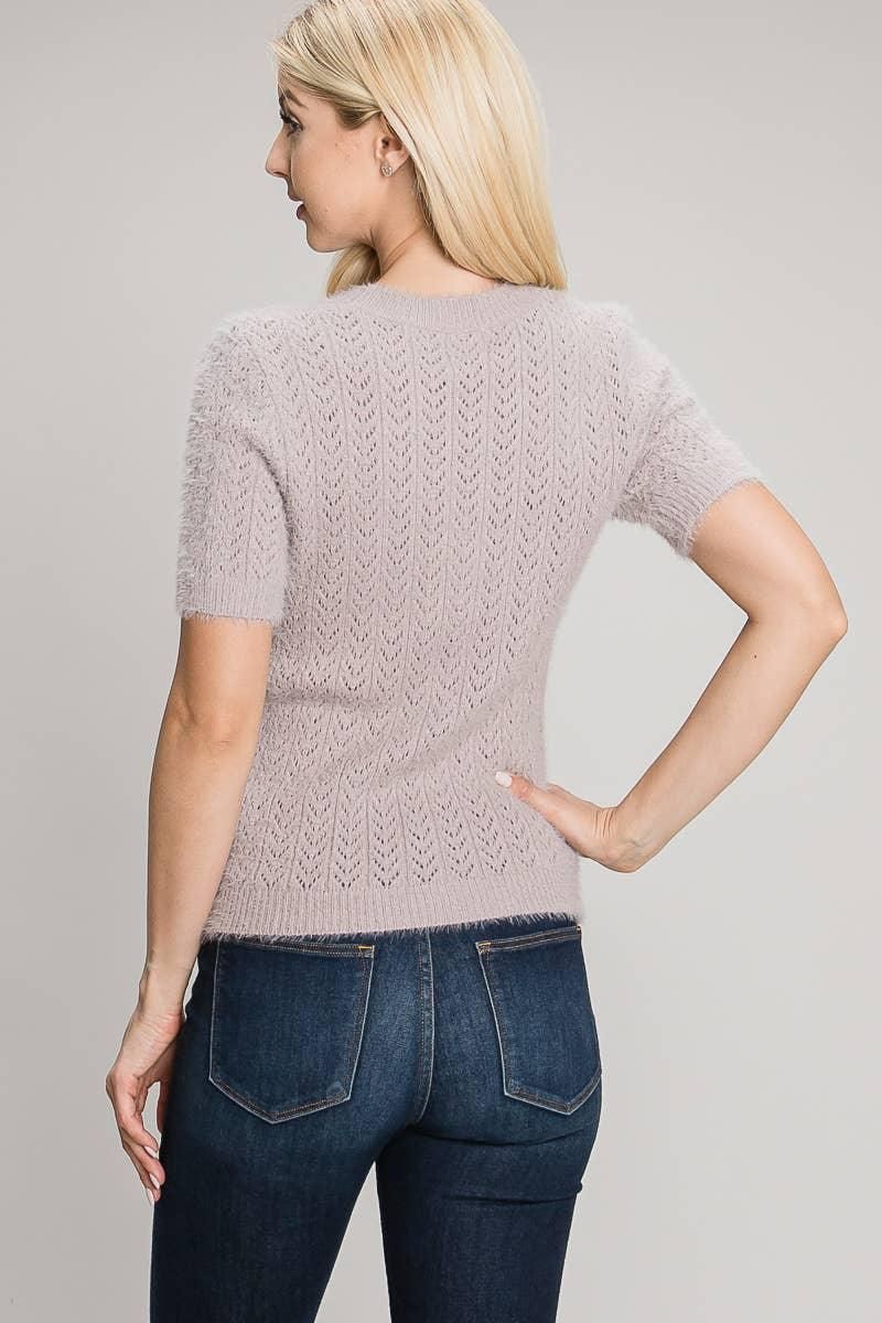 Back view of the lilac short sleeve pointelle sweater showing openwork knit detail and a ribbed hem.