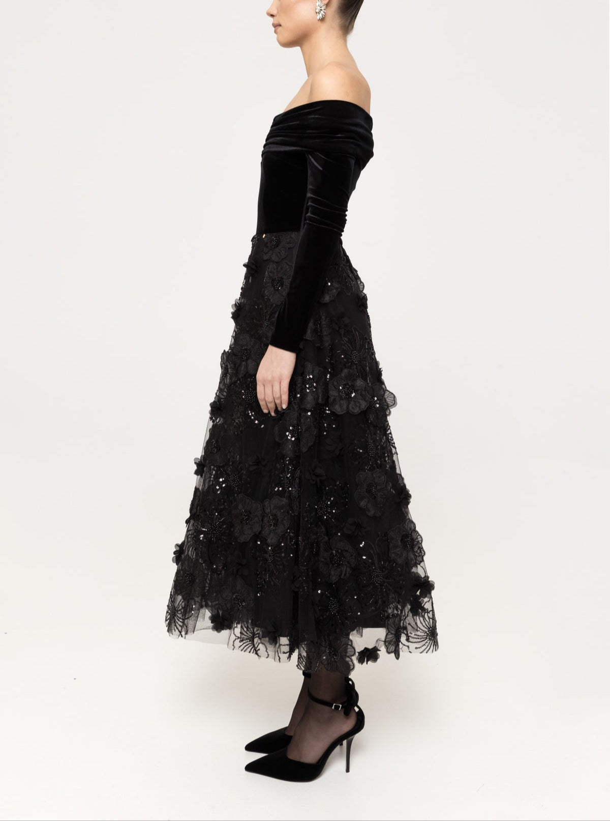 Side view of off‑shoulder velvet bodice and floral‑appliqué tulle A‑line midi skirt.
