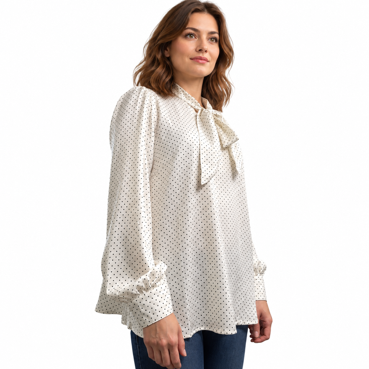 Angled view of ivory pin-dot satin blouse showing the relaxed drape, bow neckline and gathered cuffed sleeves.