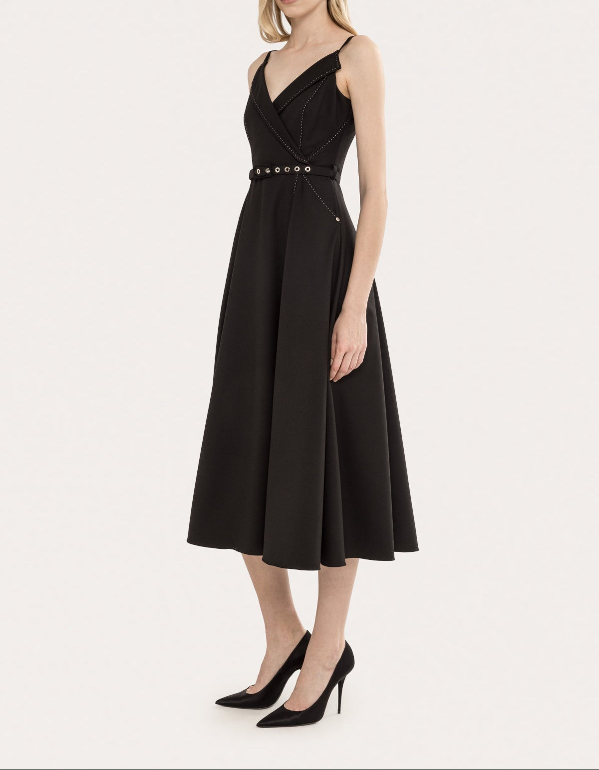 Angled front view of a black belted sleeveless V-neck A-line midi dress with contrast stitching and a polished silhouette