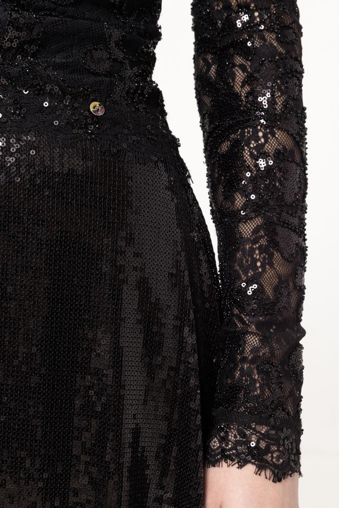 Detail of sequined lace sleeve, waist seam and micro‑sequin A‑line skirt.