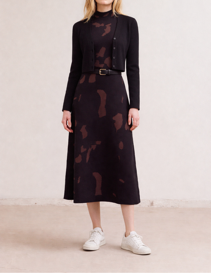 Woman wearing a black patterned fitted knit maxi dress with a matching jacket on a plain background