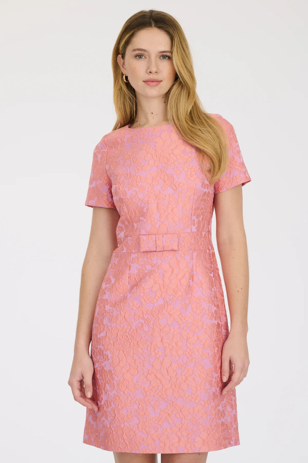 Model wearing knee-length pink jacquard dress with back zip and elegant silhouette