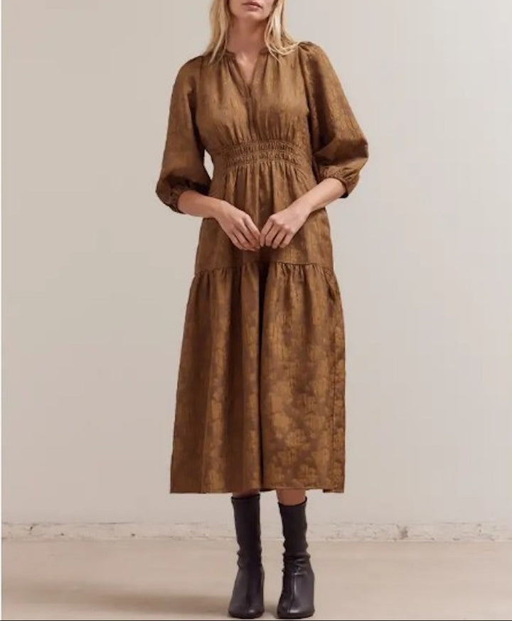 Model wearing a cacao floral jacquard midi dress with a split V‑neck, 3/4 puff sleeves, smocked waist, and tiered skirt, styled with ankle boots.