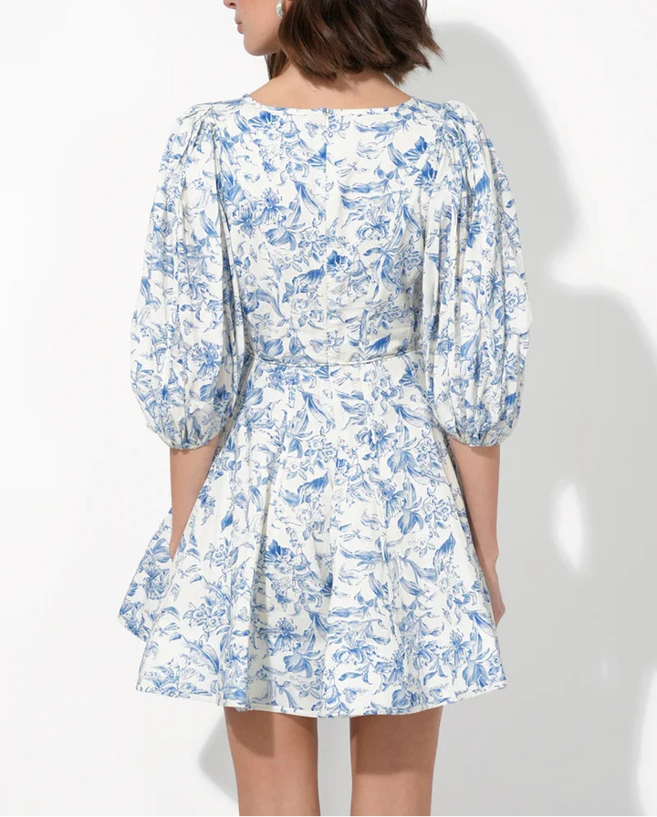 Model wearing Clare blue floral mini dress with pockets and v-neck – back view