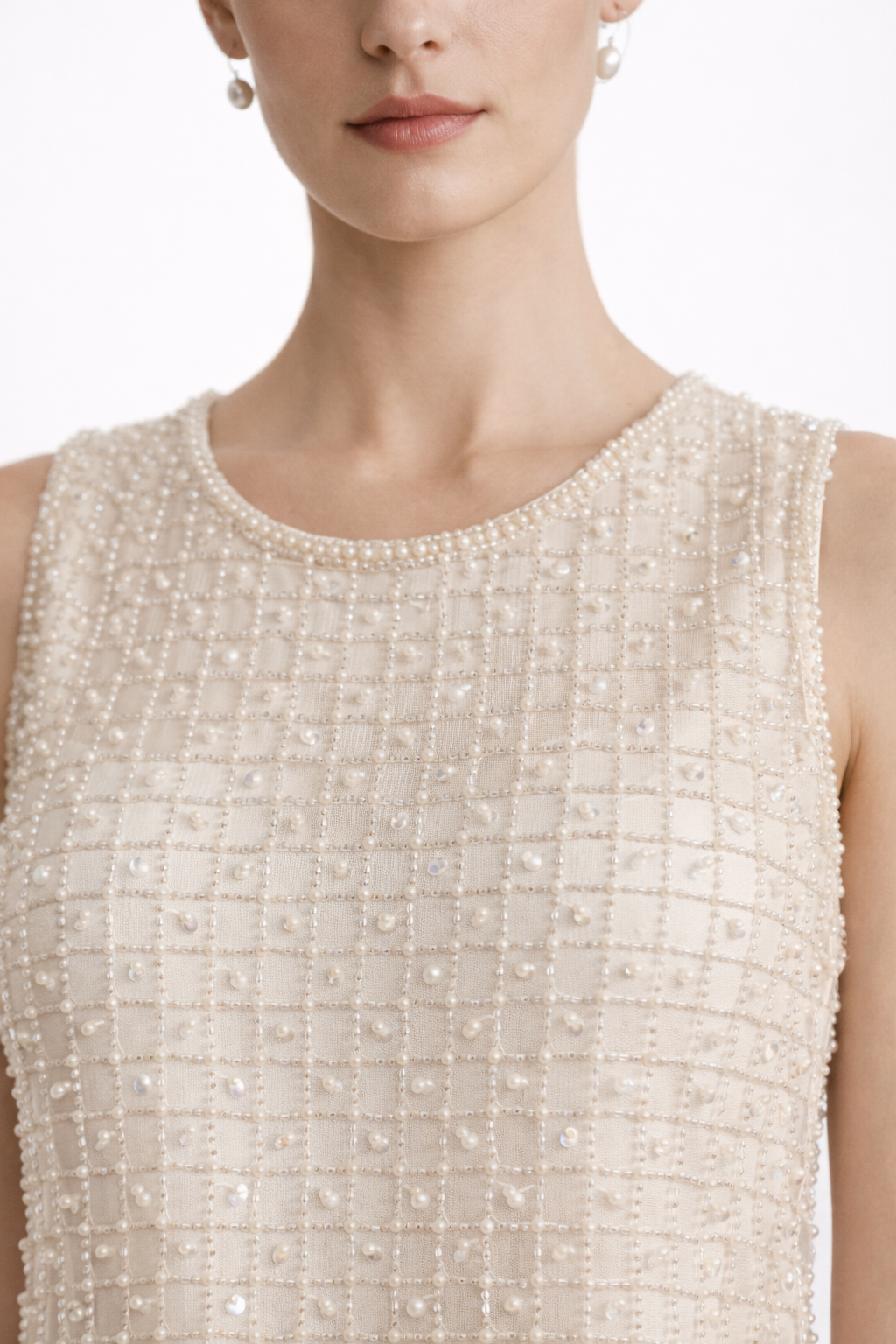 Close-up of a person wearing a sleeveless, beaded dress with a plain background