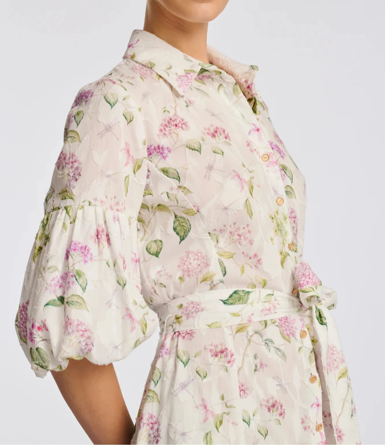 Close-up of ivory floral cotton midi shirt dress with shirt collar, gold buttons, and puff sleeves