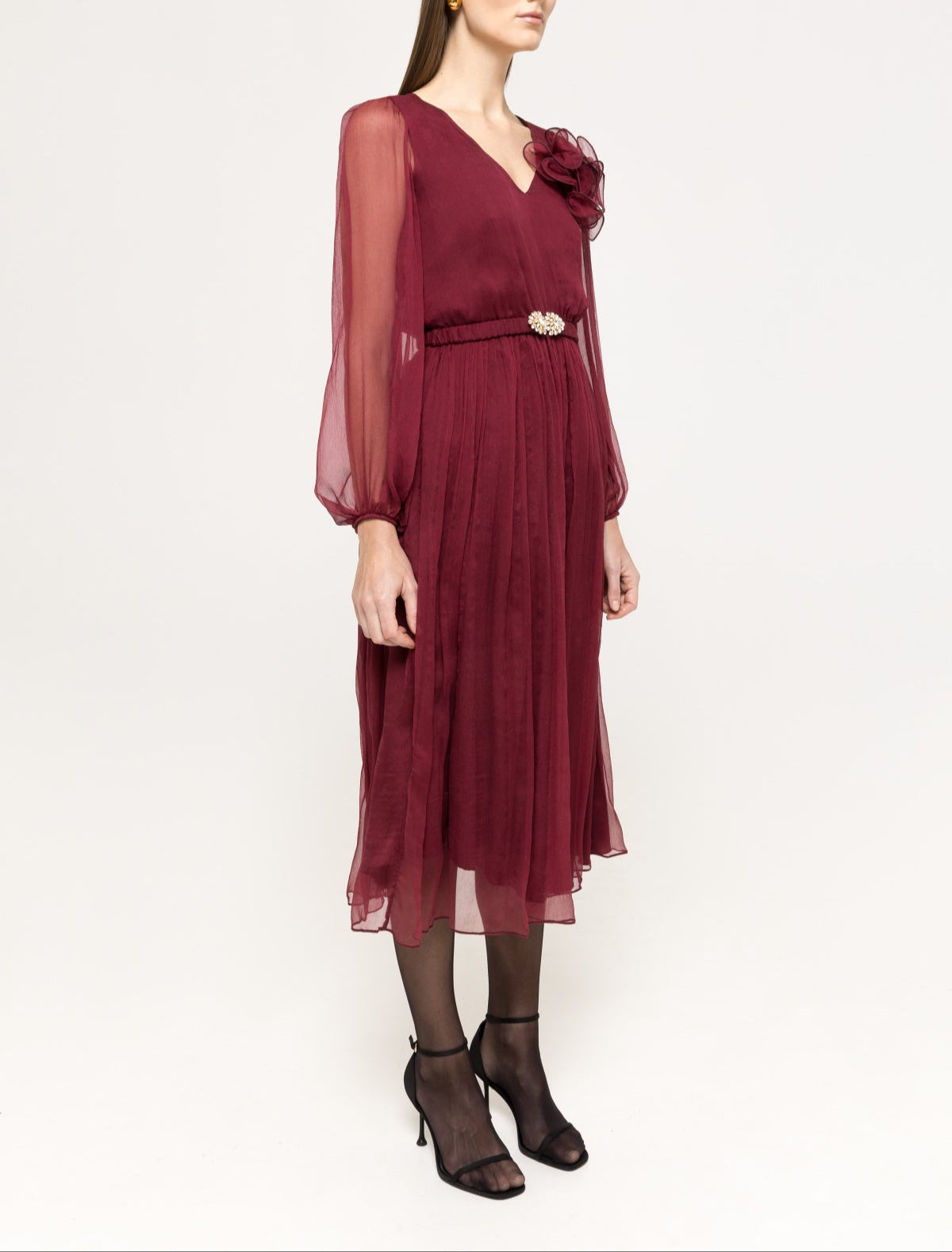 Wine midi with V‑neck, airy sleeves, 3D flower at shoulder and pleated skirt.