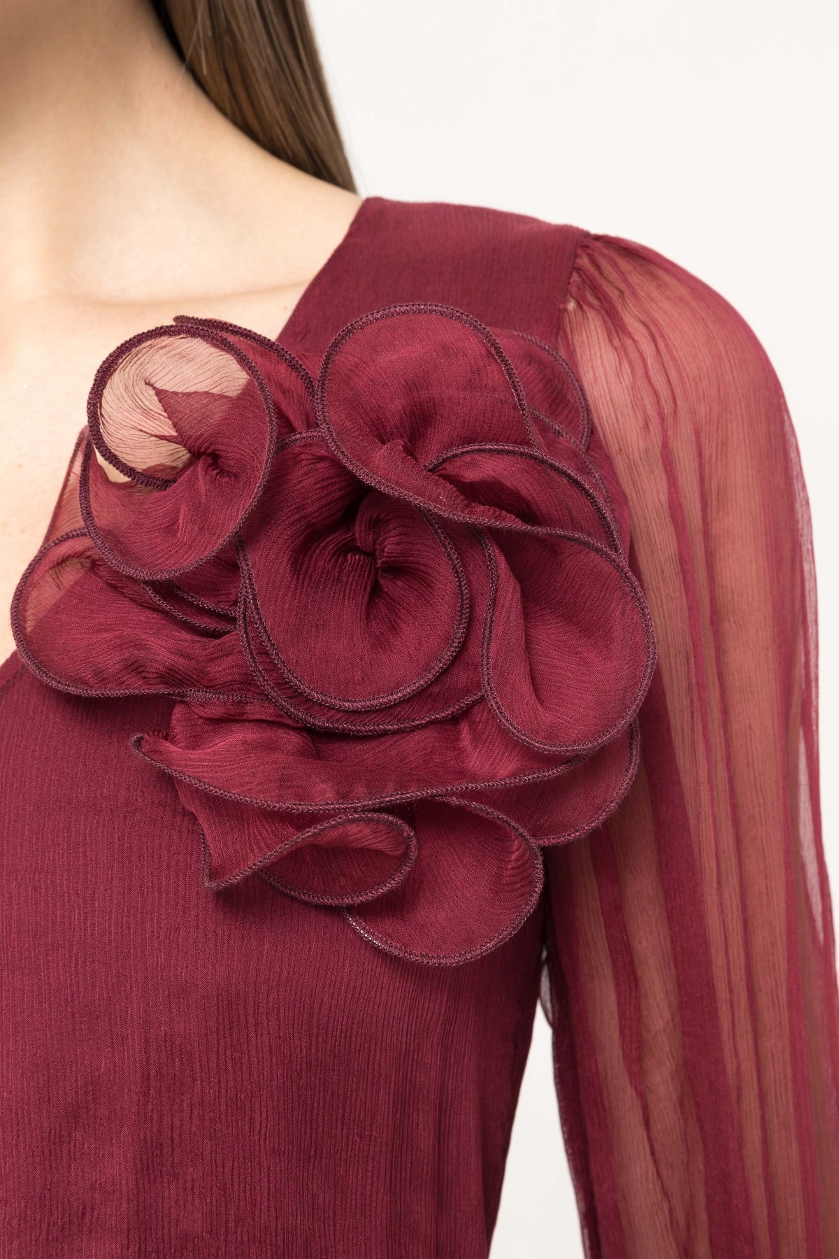 Wine midi with V‑neck, airy sleeves, 3D flower at shoulder and pleated skirt.