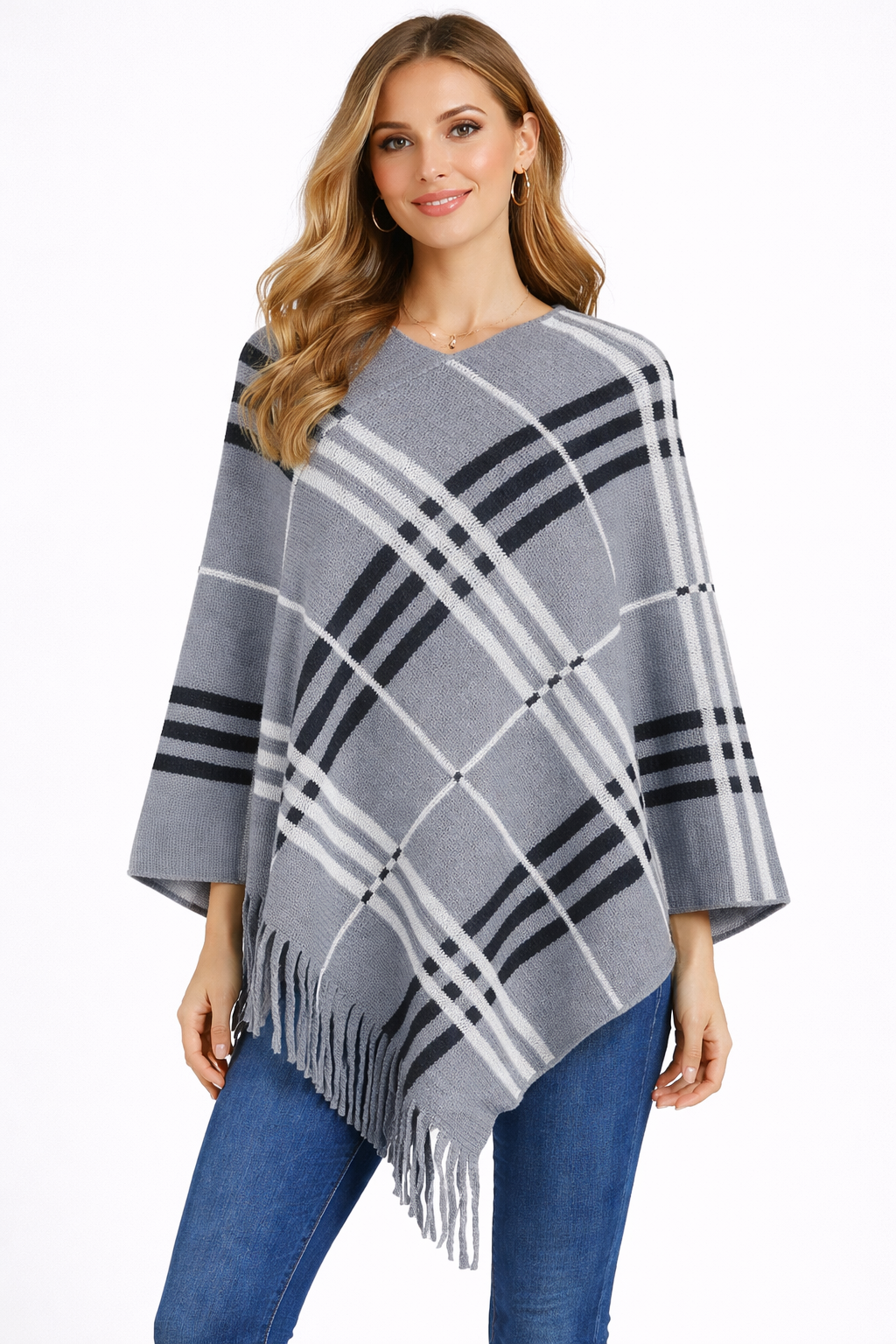 Woman wearing a gray and black plaid poncho with fringe on a white background
