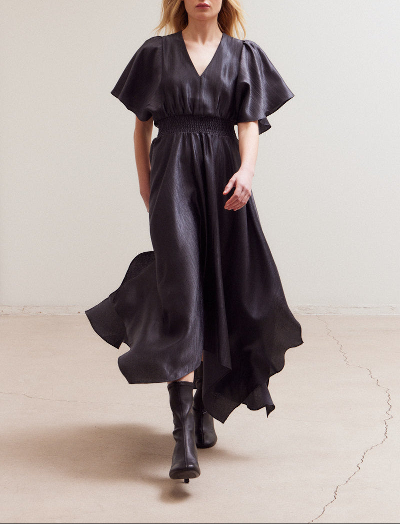 Front view of model wearing midnight satin maxi dress with flutter sleeves and handkerchief hem.