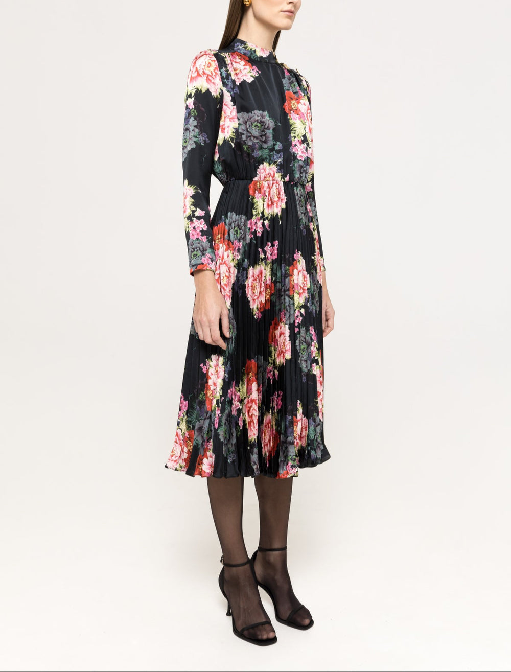 Three‑quarter view of black floral pleated midi with defined waist and knife‑pleated A‑line skirt