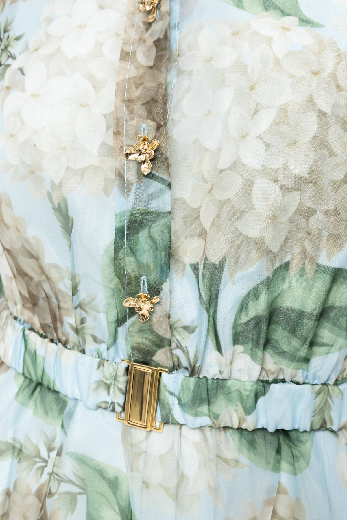 Detail of sage green hydrangea print organza midi dress featuring gold buckle belt and floral button hardware