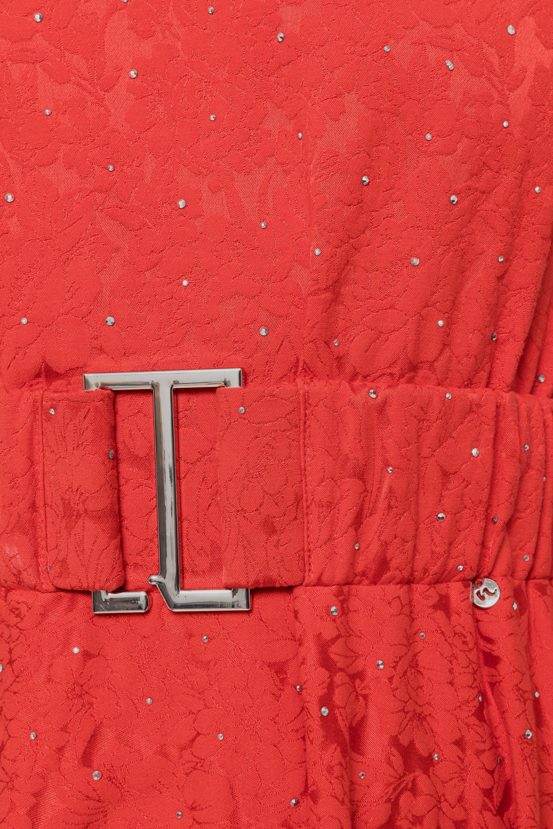 Close-up of a red textured fabric with a silver belt buckle.