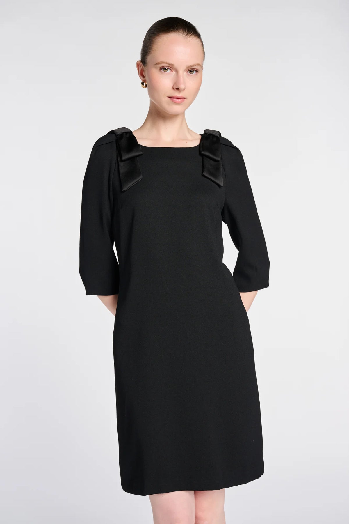 Front view of WEILL black shift dress showing its round neckline, satin shoulder bows and three-quarter sleeves.
