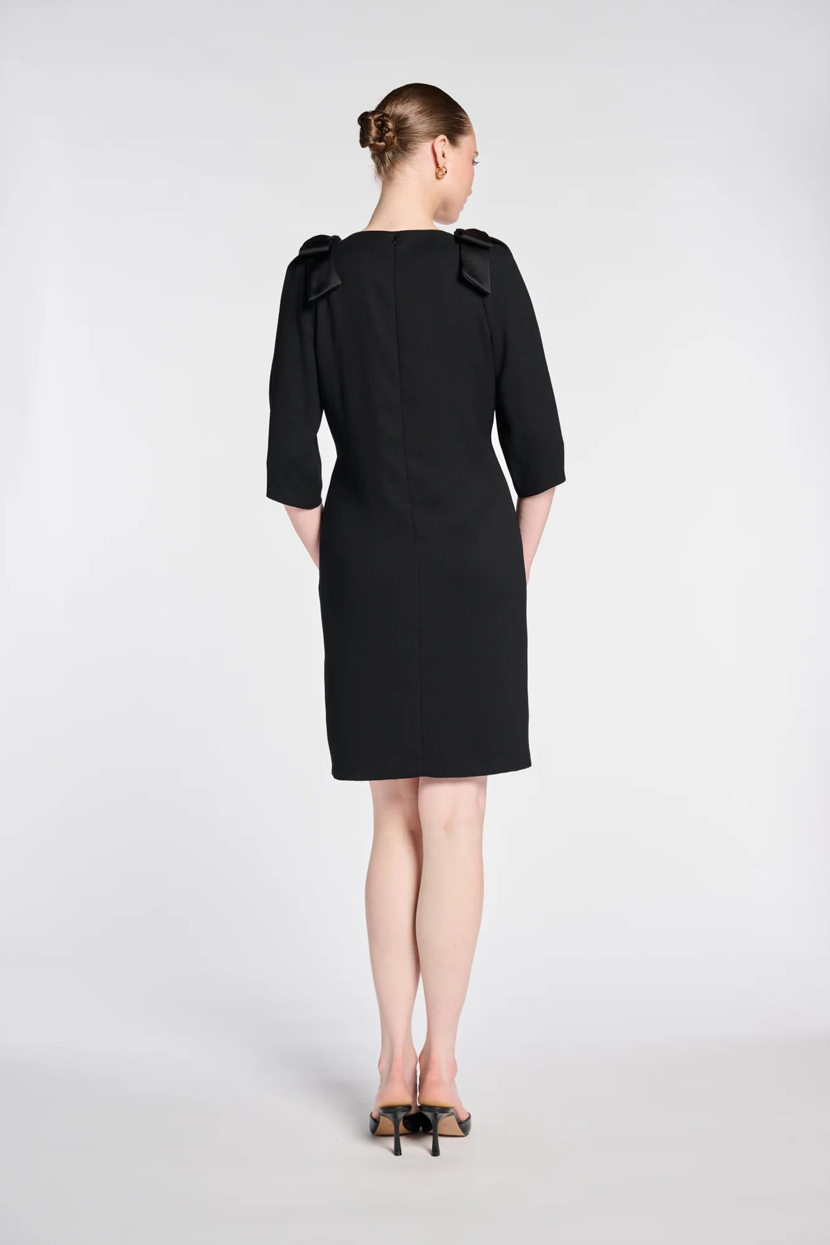 Back view of WEILL black cocktail dress with satin shoulder bow details, three-quarter sleeves and a straight hem.