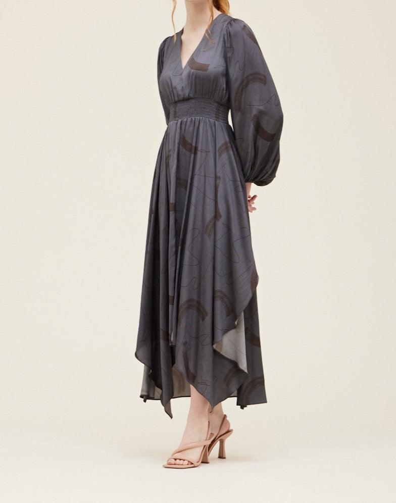 Three-quarter view of the Grade & Gather Slate satin maxi dress showing the pointed asymmetrical hem.