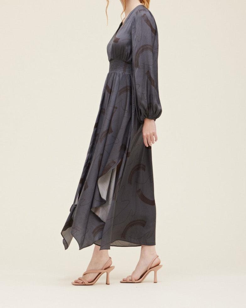 Side view of the Grade & Gather Slate gray satin maxi dress showing the long sleeve and draped uneven hem.