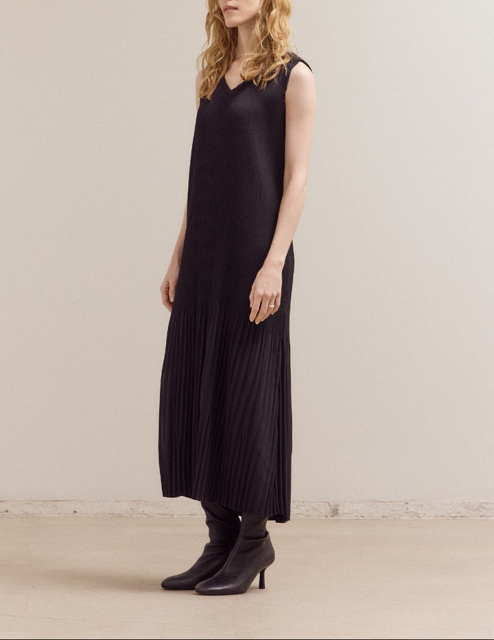 Woman wearing a black sleeveless dress against a plain background