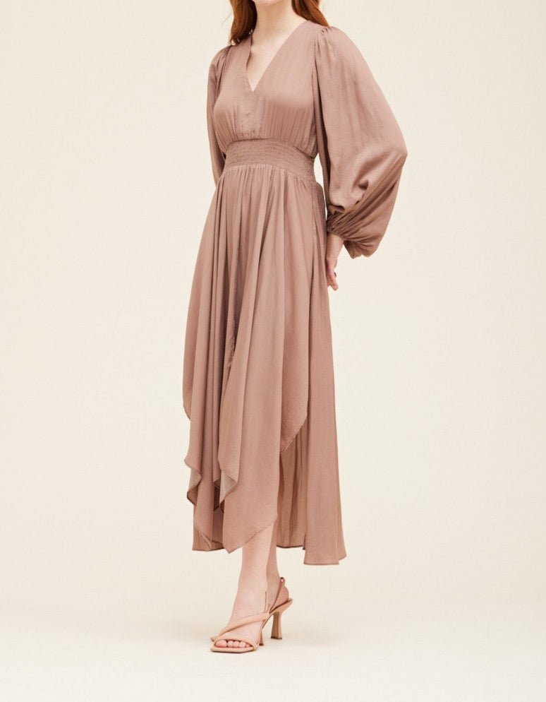Side view of dusty orchid satin maxi dress highlighting the flowy skirt, smocked waistband, and sheer long sleeves.