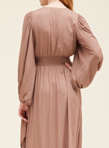 Close-up of smocked elastic waist on dusty orchid satin maxi dress with long balloon sleeves.