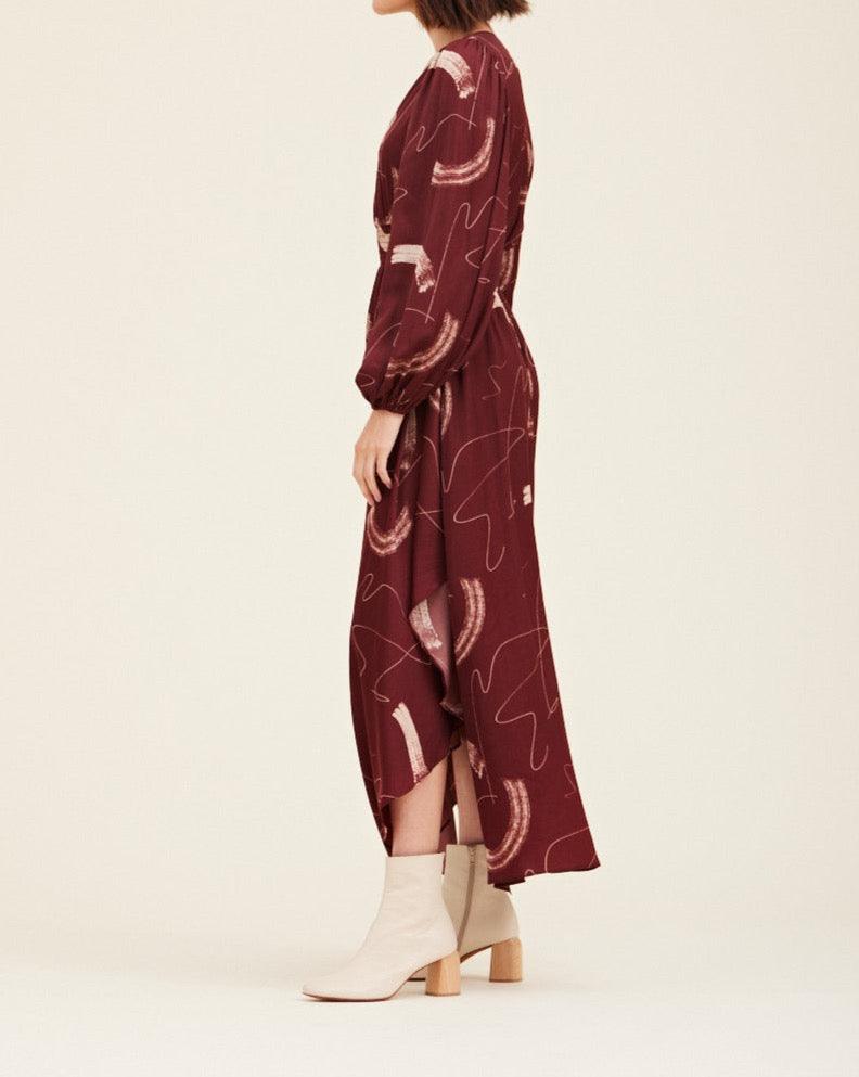 Side view of the Grade & Gather Vino abstract satin maxi dress showing the long sleeve and uneven hem.