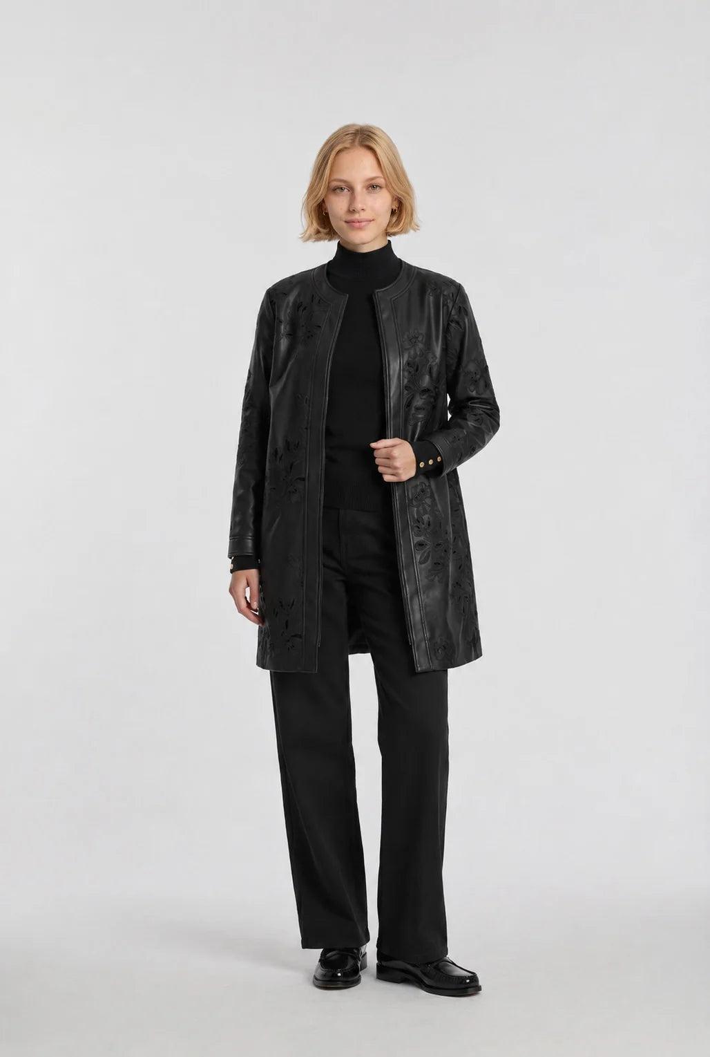 Weill Paris black floral embroidered faux leather coat worn open over a black knit and trousers, front view.