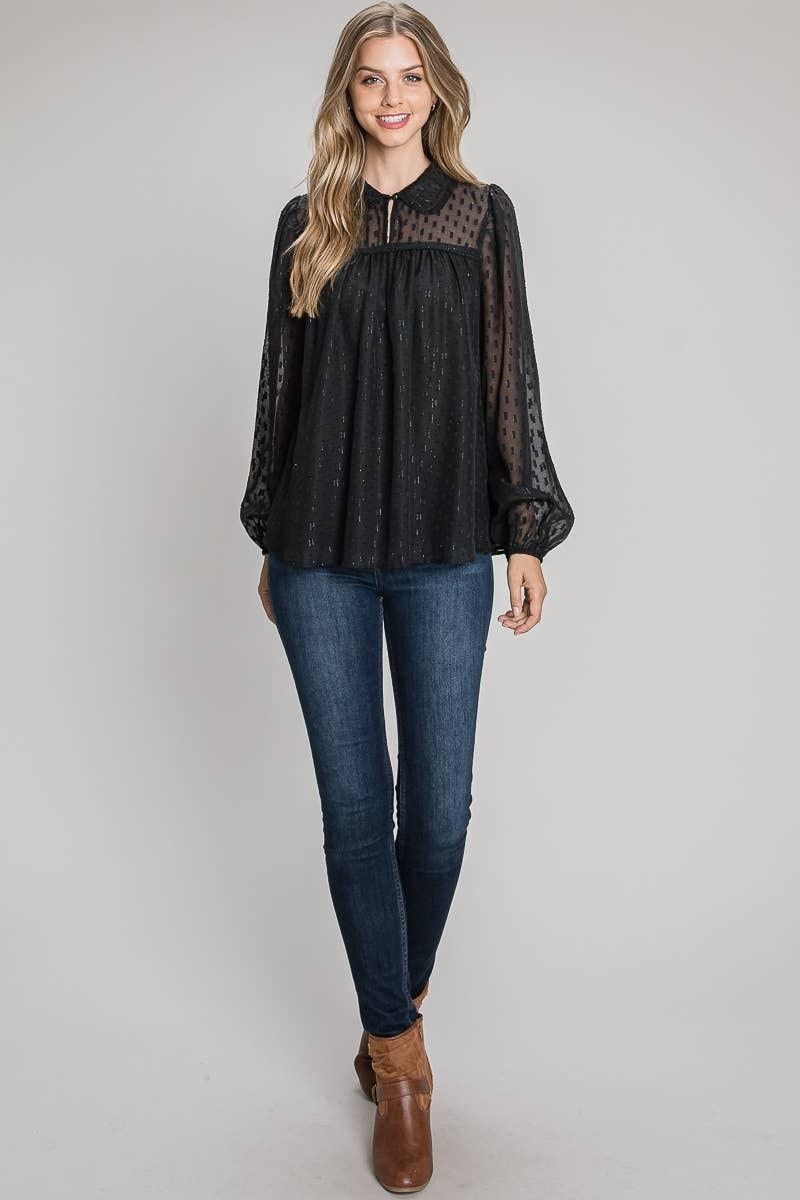 Model wearing the black geo lurex collared blouse untucked with blue jeans and brown ankle boots.