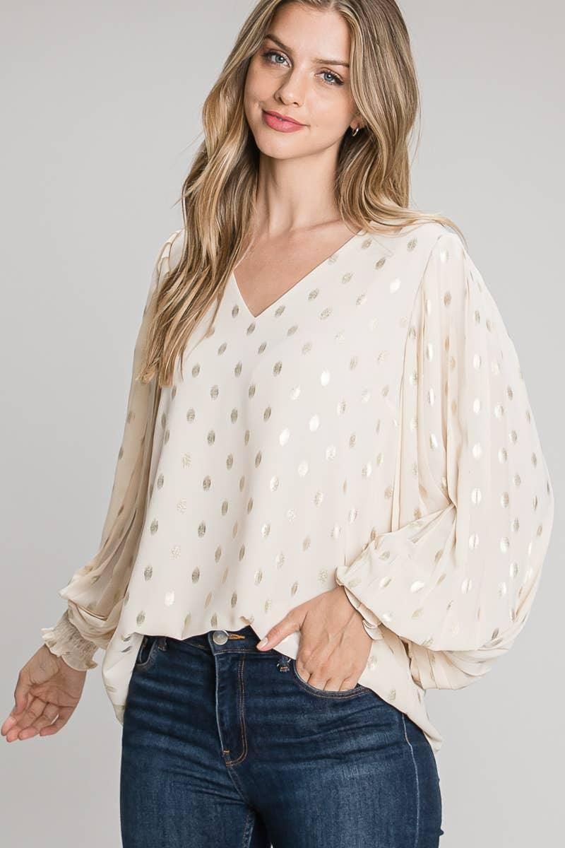 Front view of the Allie Rose champagne foil dot blouse with a V-neck, full long sleeves and smocked cuffs, styled with dark jeans.