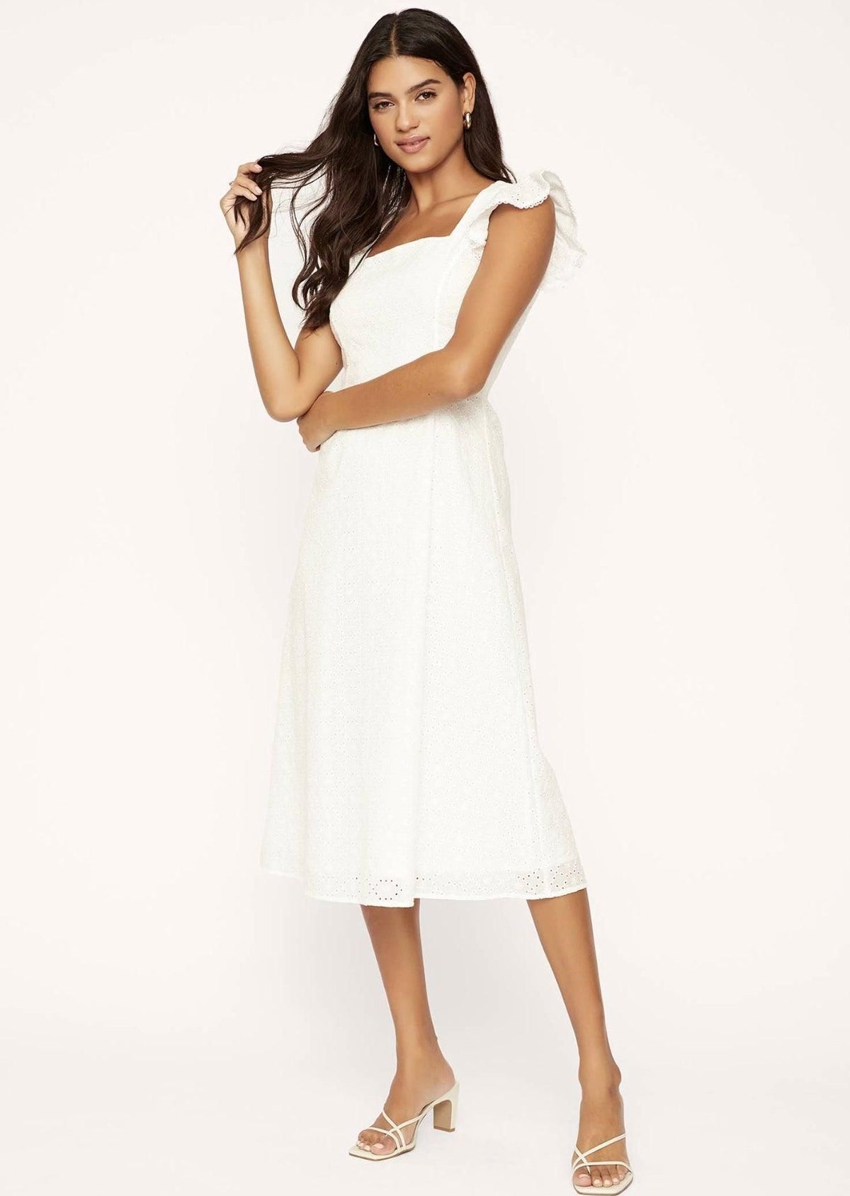 Angled front view of the Hoku Hawaii white eyelet midi dress, showing the ruffled shoulder detail and flared skirt.