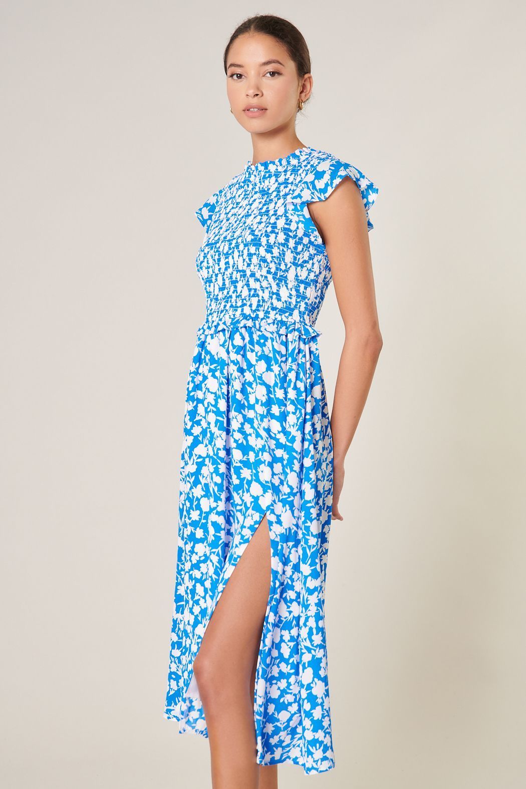 Side view of blue and white printed midi dress with smocked bodice and flowing skirt