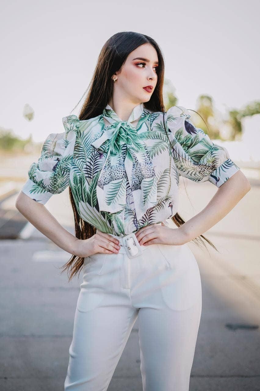 Like the Moon green botanical tie-neck blouse with short puff sleeves, styled with white trousers.